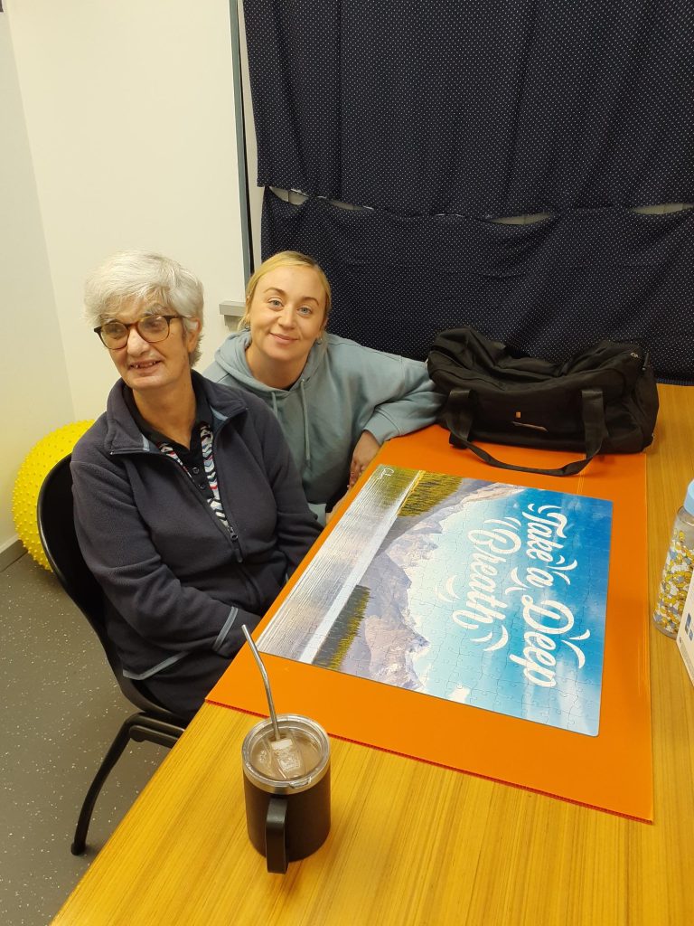 Rocky Bay support worker and customer sitting together and smiling at the camera.