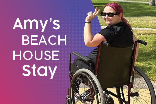 A Rocky Bay customer who is a wheelchair user is smiling at the camera and presenting the peace signs with her hands.