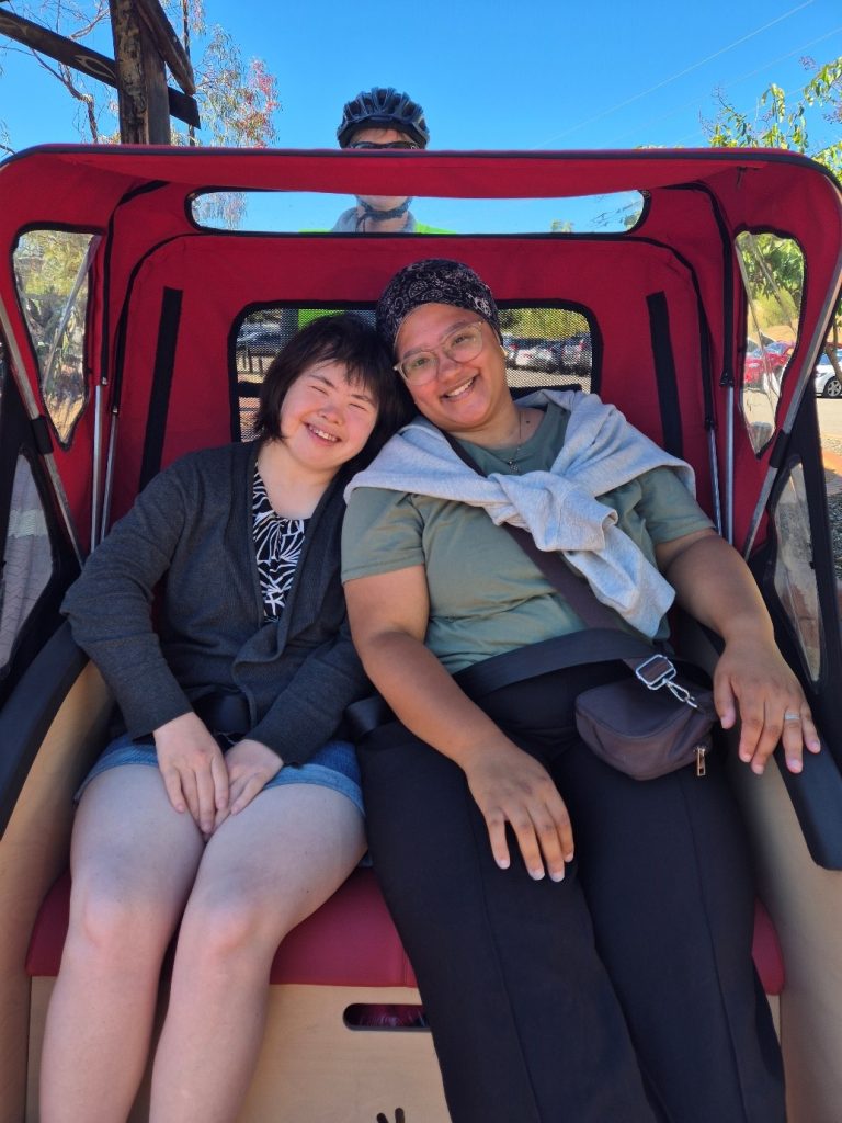 Rocky Bay customer and support worker enjoying a day out riding a rickshaw ride