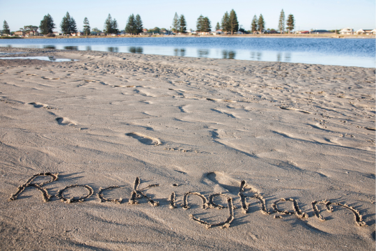 The word Rockingham written in the sand at the beach.