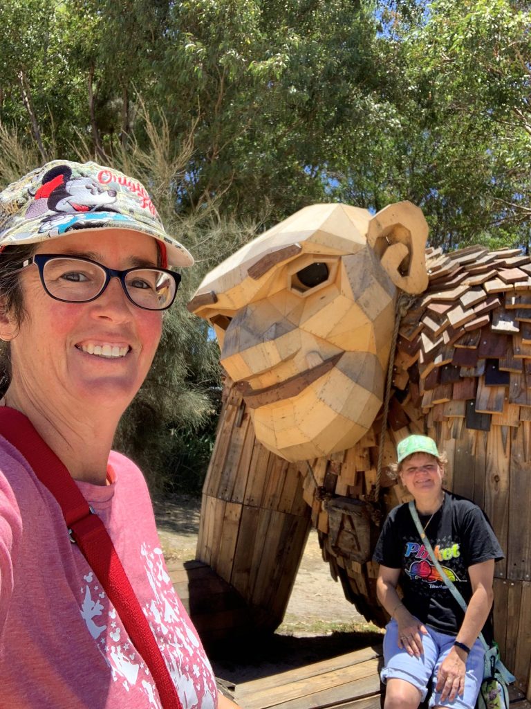 Rocky Bay customer and support worker pose for a photo with art sculptures behind them.