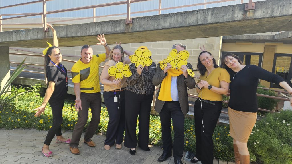 7 staff stand wearing yellow.