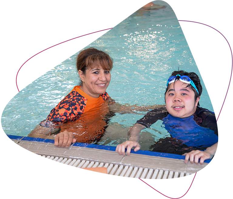 Rocky Bay Senior Allied Health Assistant Sam and Customer Steven are smiling at the camera. They are sitting in a pool during Steven's Hydrotherapy session.