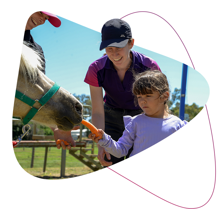 Rocky Bay customer Kennedy feeding a horse during her hippotherapy sessions.